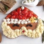 A Santa shaped Christmas butter board with rosemary sprigs and bread.