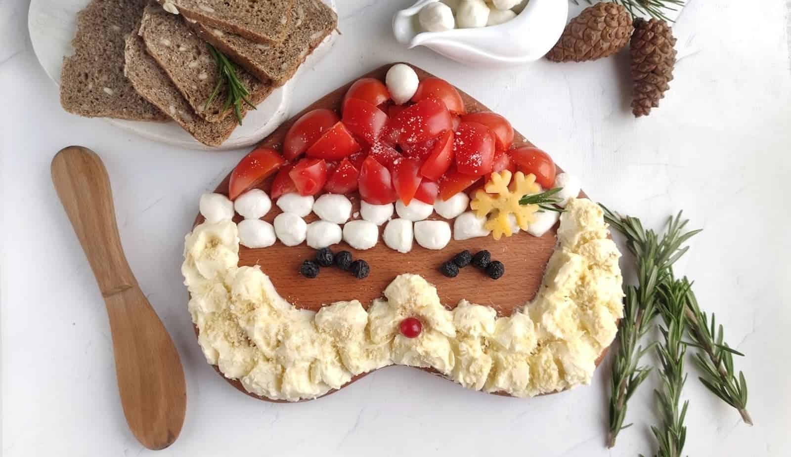 A Santa shaped Christmas butter board with rosemary sprigs and bread.