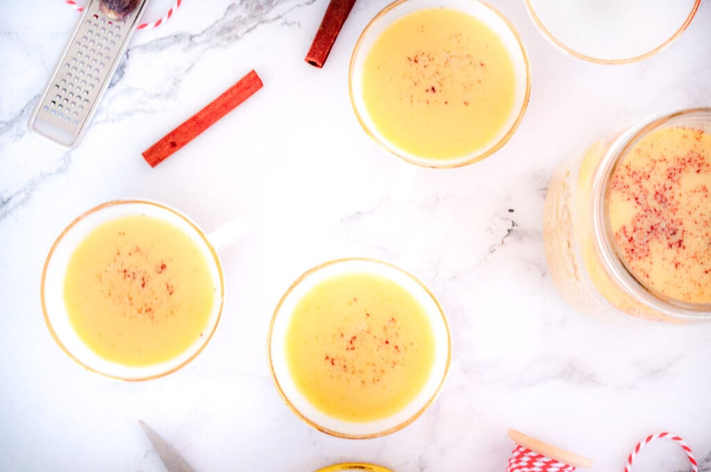 A group of cups with cinnamon and ginger on a marble table.