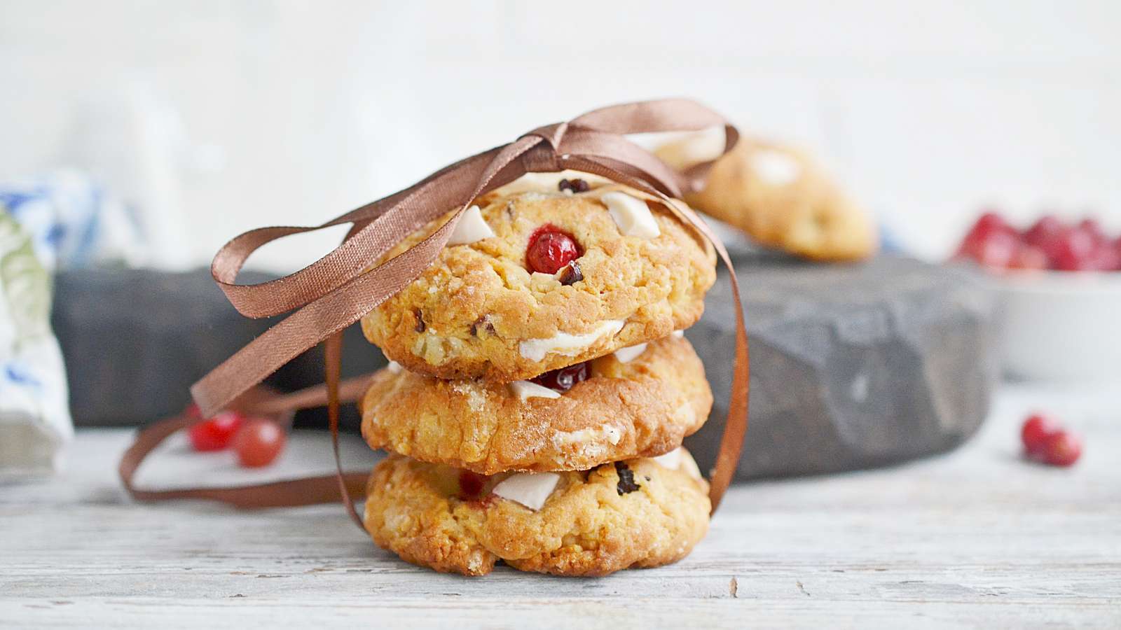 A stack of cookies with cranberries and white chocolate chips on top.