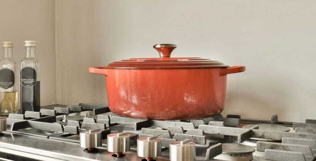 A red dutch oven sits on top of a stove.