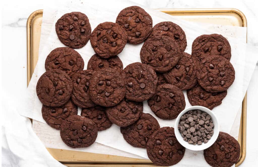Chocolate chip cookies on a tray with chocolate chips.