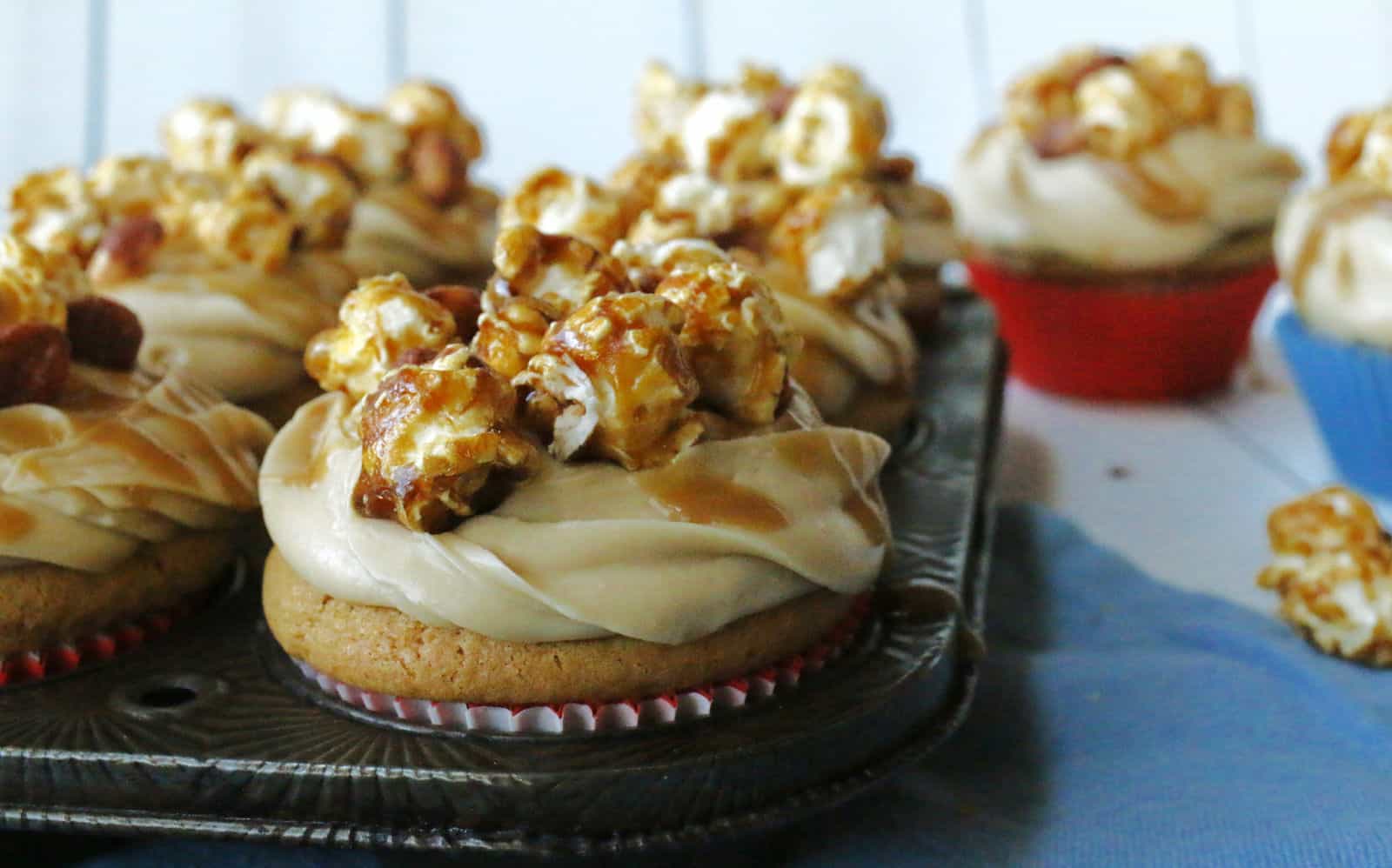 A tray of cupcakes topped with caramel and popcorn.