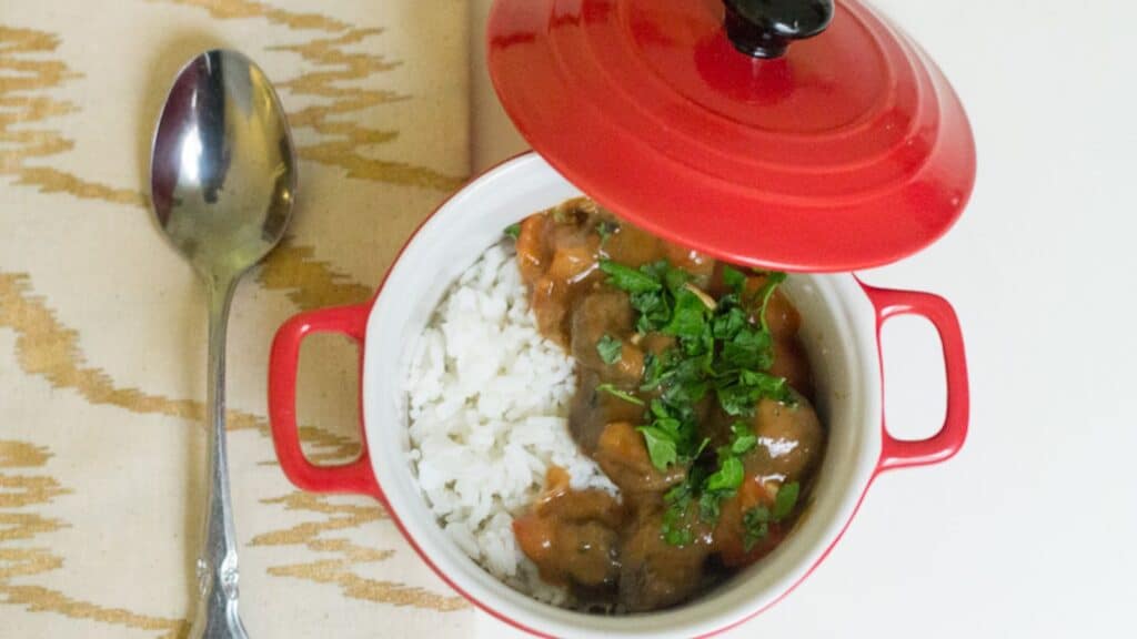 A red pot with rice and a spoon next to it, perfect for veggie mains.