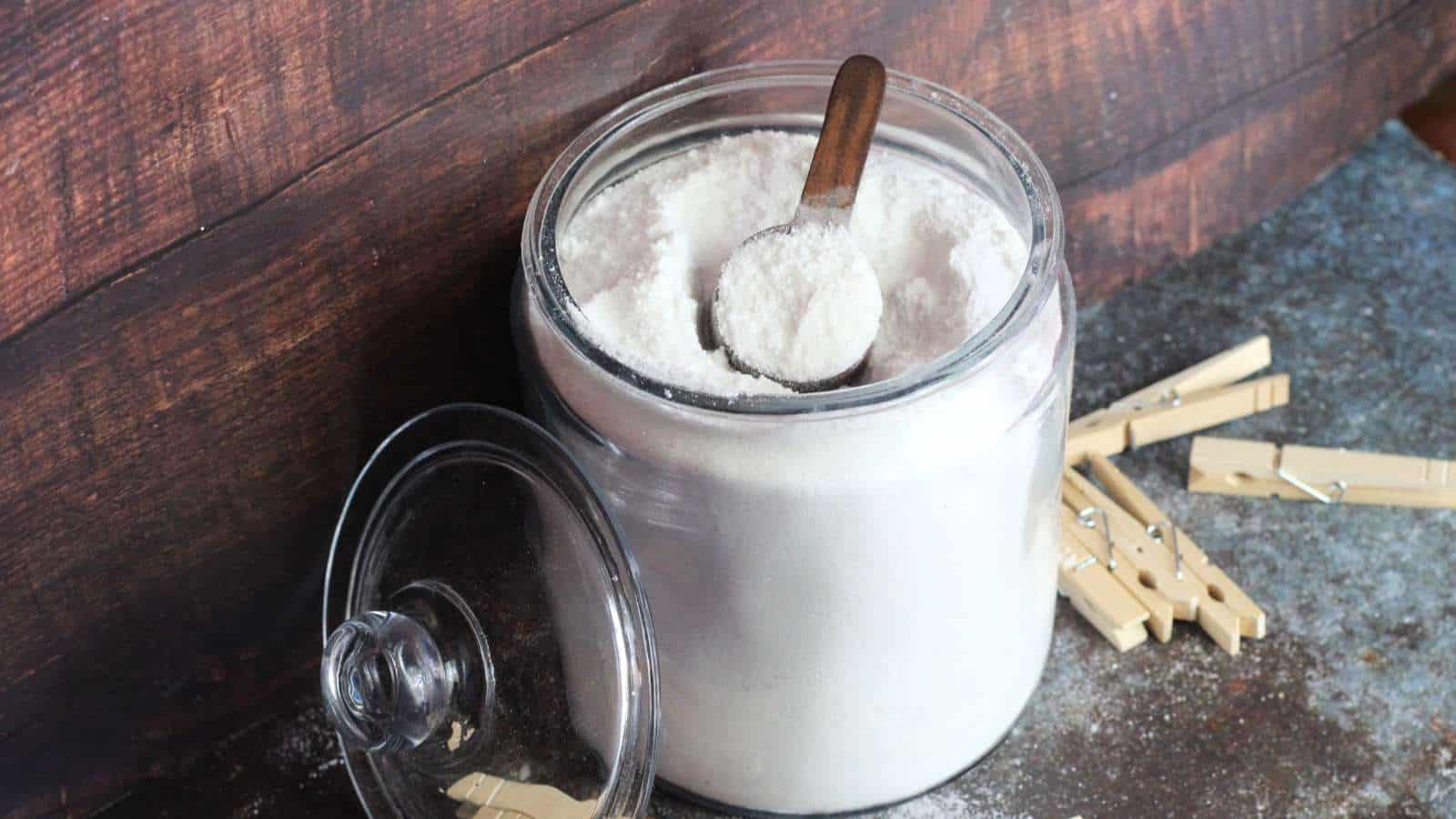 A jar of homemade laundry detergent next to a wooden spoon.