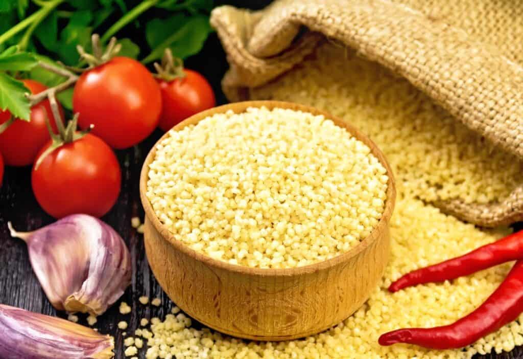 Couscous, tomatoes and garlic on a wooden table.