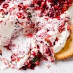 A plate with cranberry cream cheese and crackers.