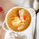 A bowl of chicken noodle soup with vegetables and a spoon.