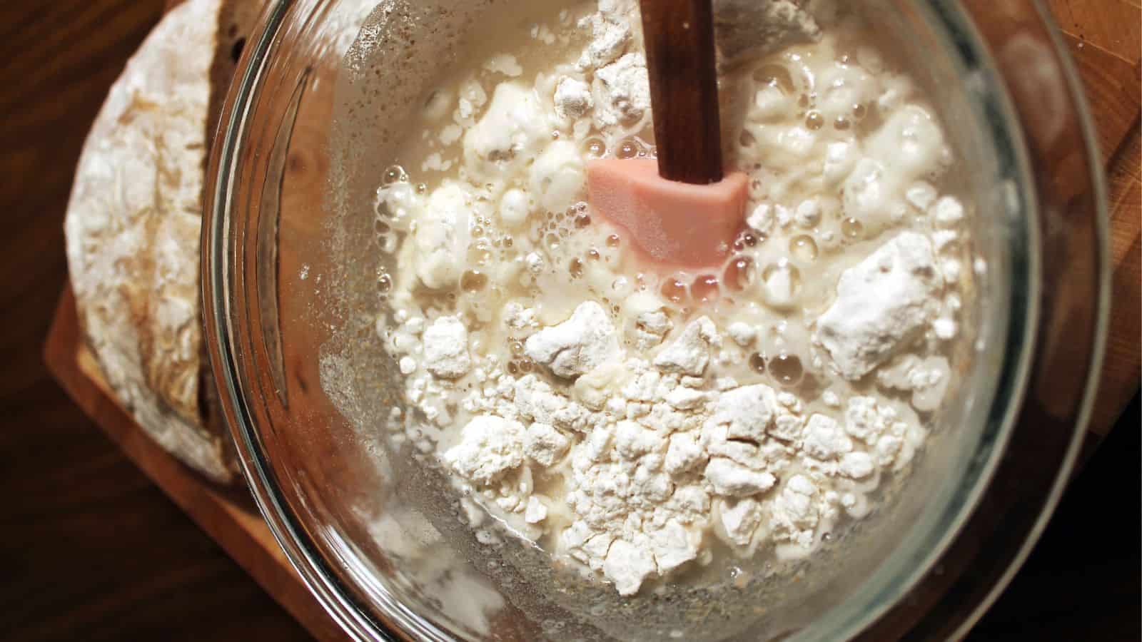 A bowl of flour with a spatula in it.