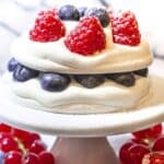 Pavlova topped with berries and whipped cream.