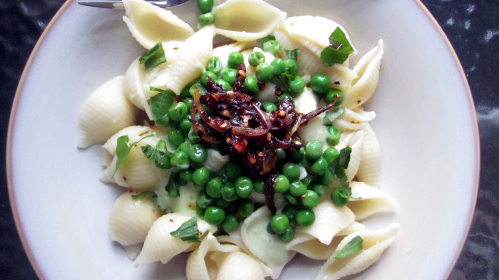 A plate with pasta and peas on it.