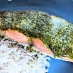 Image shows Salmon with pesto and rice on a blue plate.