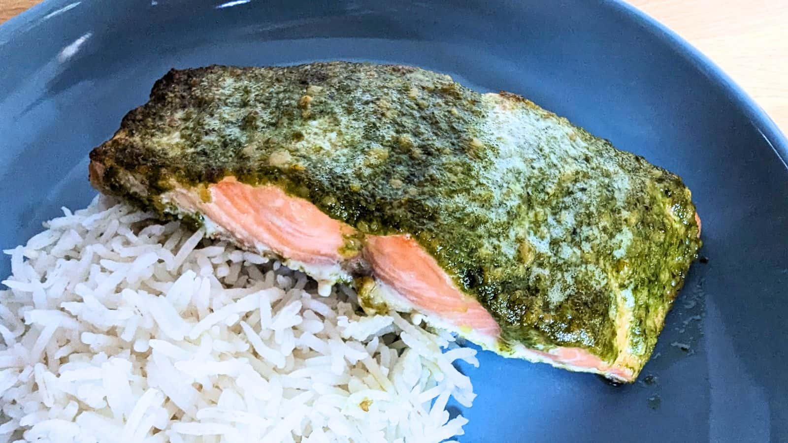 Image shows Salmon with pesto and rice on a blue plate.