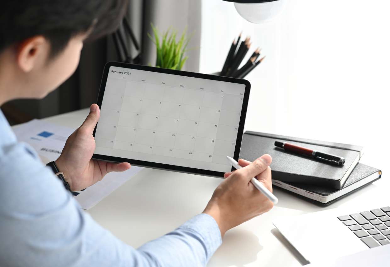 A man is looking at a calendar on an ipad.