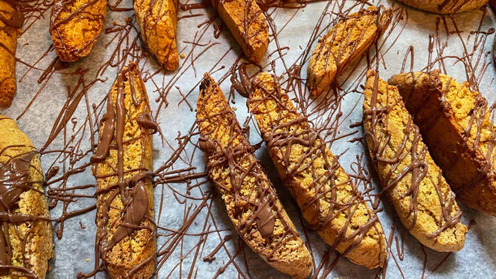 A tray of pumpkin biscotti with chocolate drizzle on them.