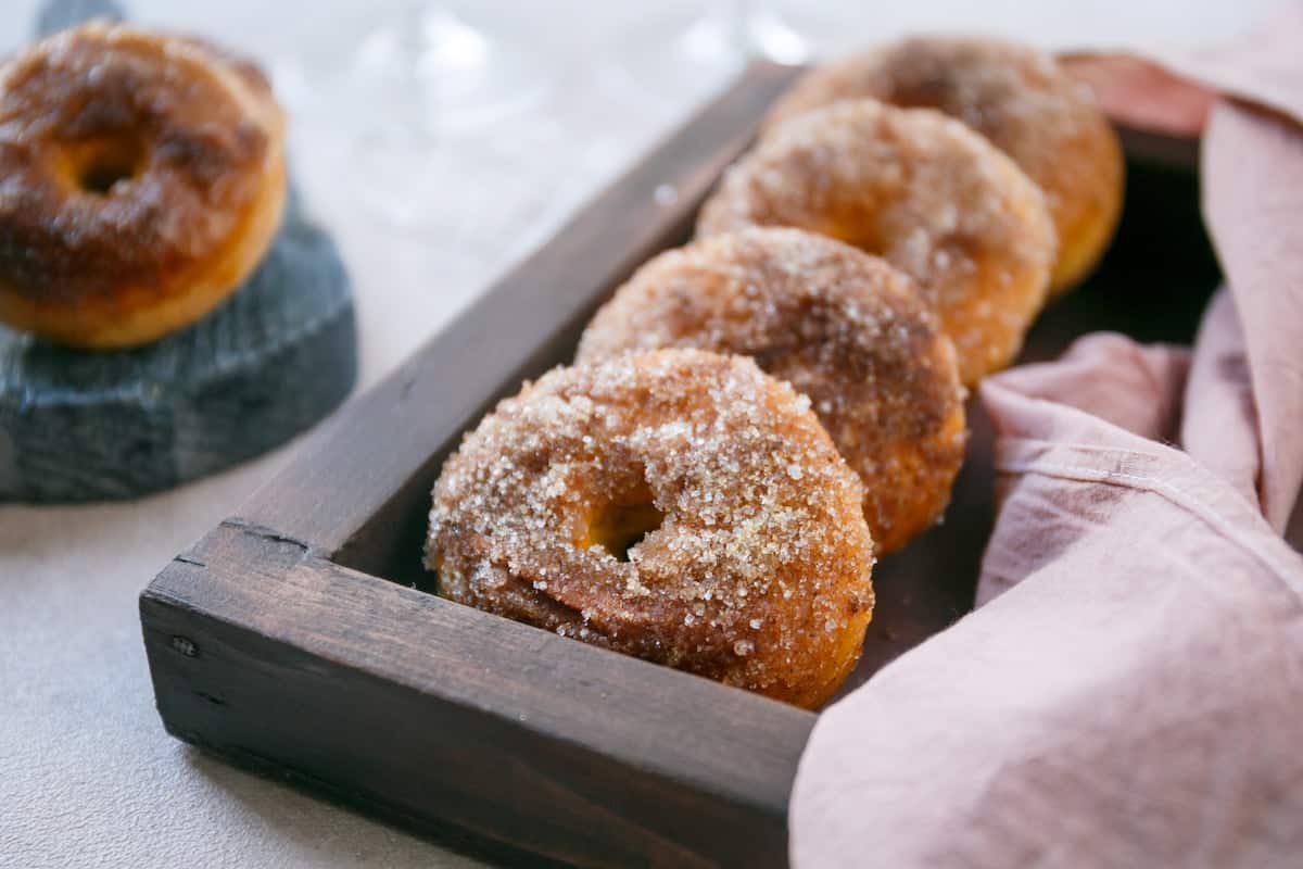 Four baked pumpkin donuts in a tray.