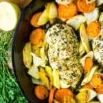 Roasted chicken and vegetables in a skillet on a cutting board.