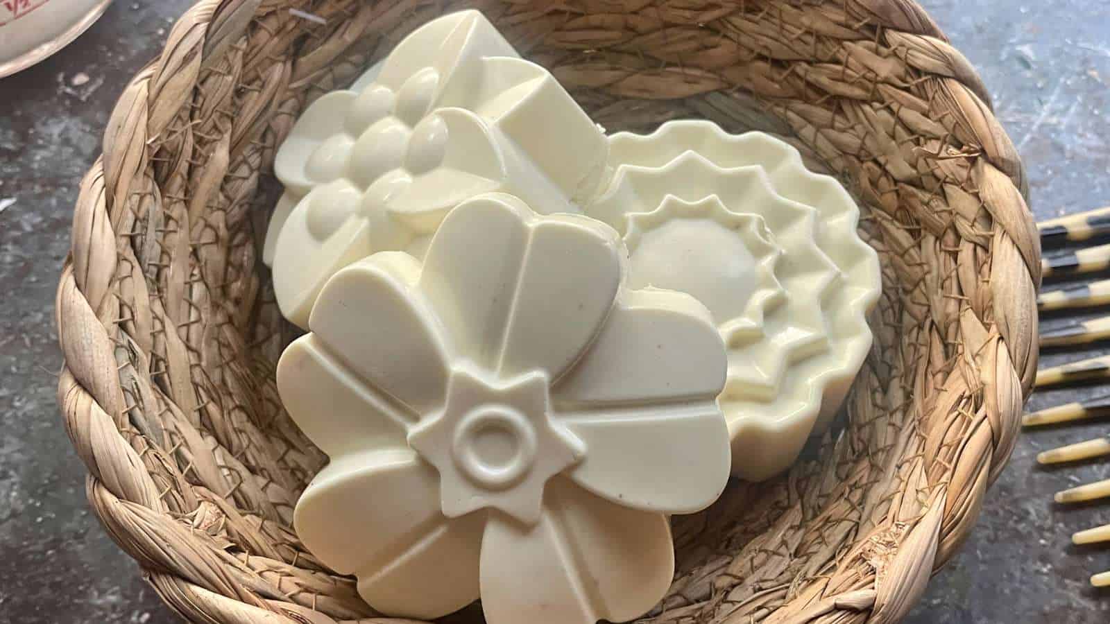 White homemade shampoo bars in a wicker basket next to a pair of scissors.