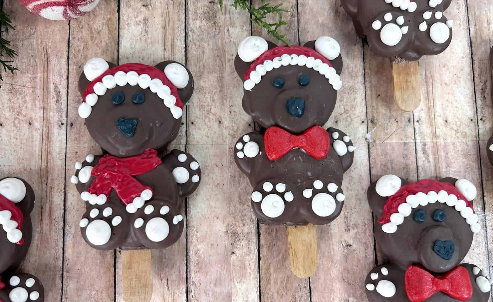 Chocolate-covered Santa teddy bear Oreo pops on wooden background.