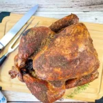 A smoked turkey on a wooden cutting board.