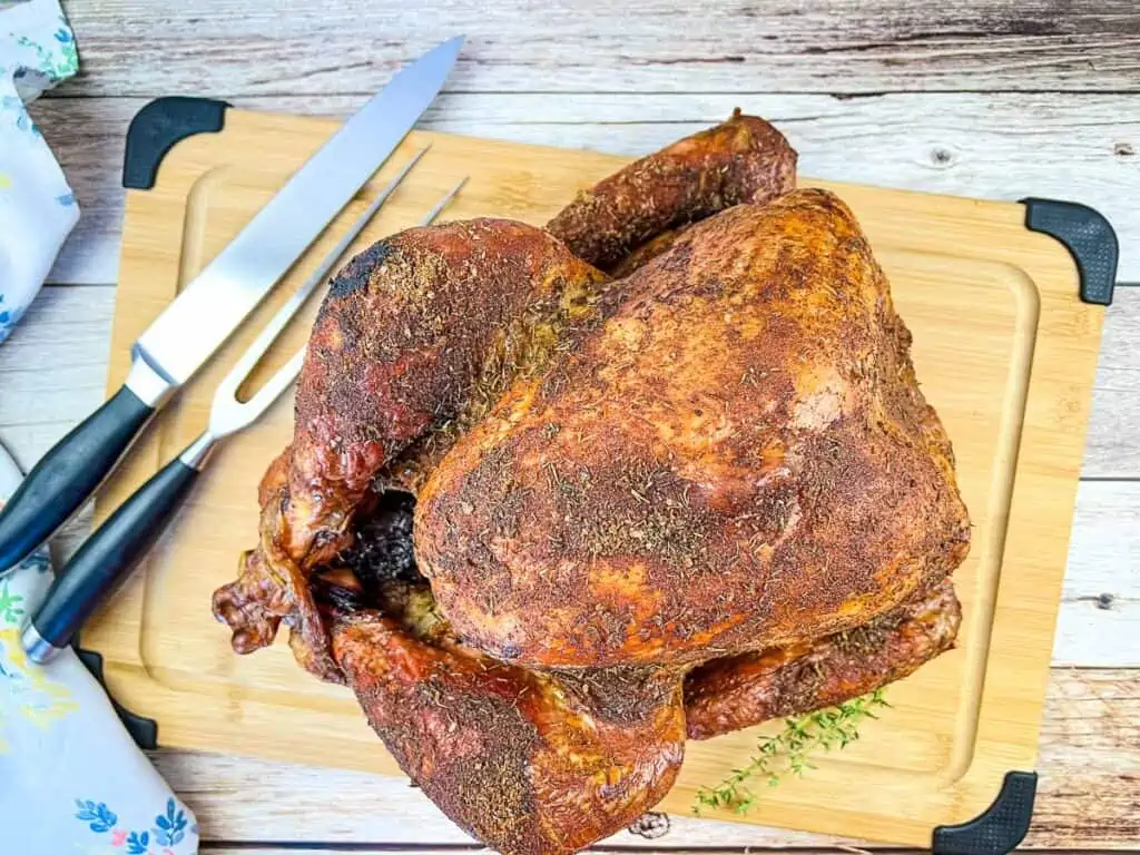 A smoked turkey on a wooden cutting board.