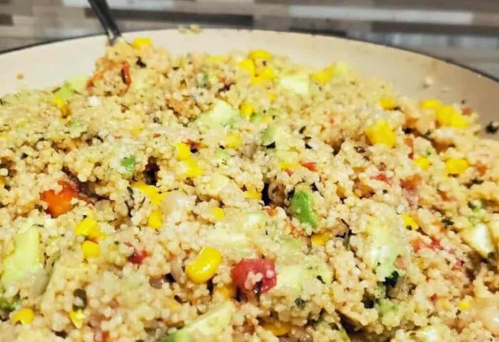 A bowl of quinoa salad with vegetables and corn.