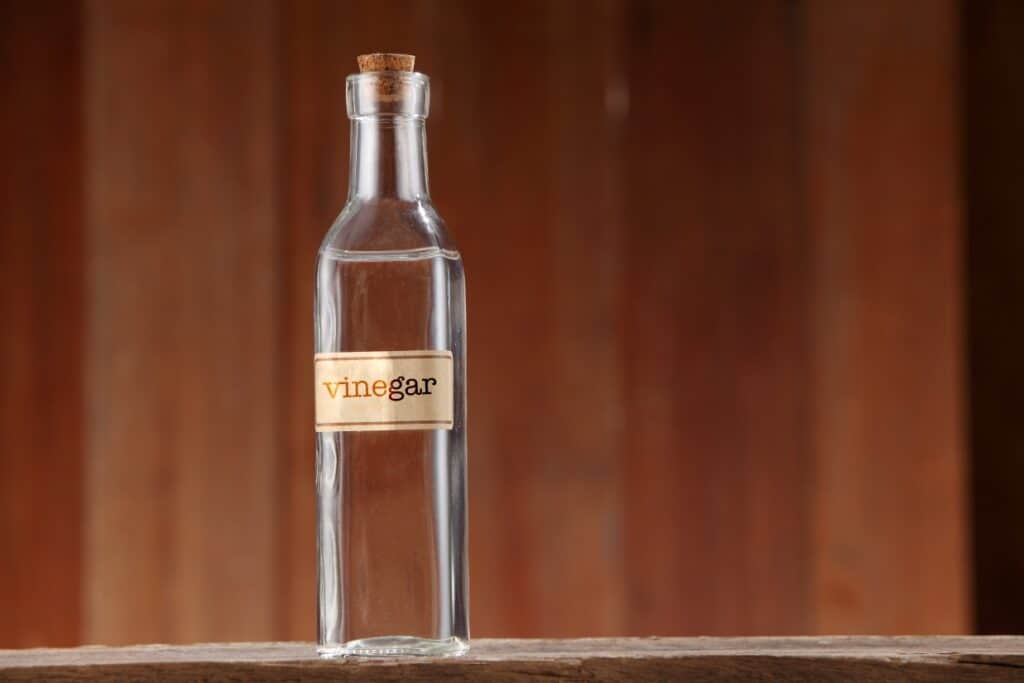 A bottle of vinegar sitting on a wooden table.