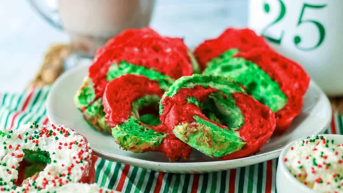 Christmas bagels on a plate with green and red sprinkles.