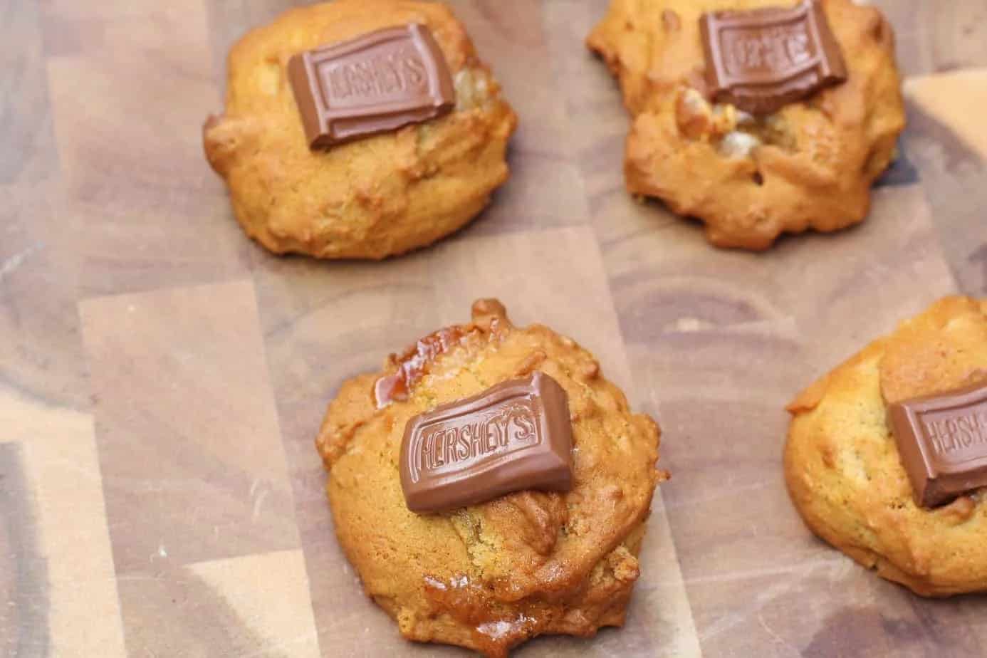 Wooden cutting board with cookies on top.