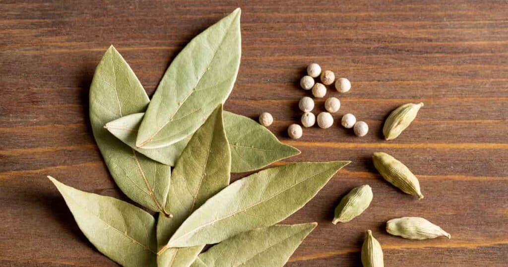 A bunch of dried bay leaves and seeds on a wooden table.