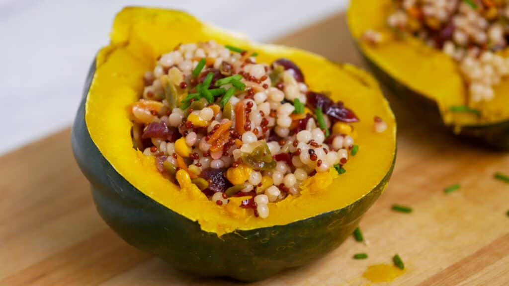 Two stuffed acorn squash on a cutting board.