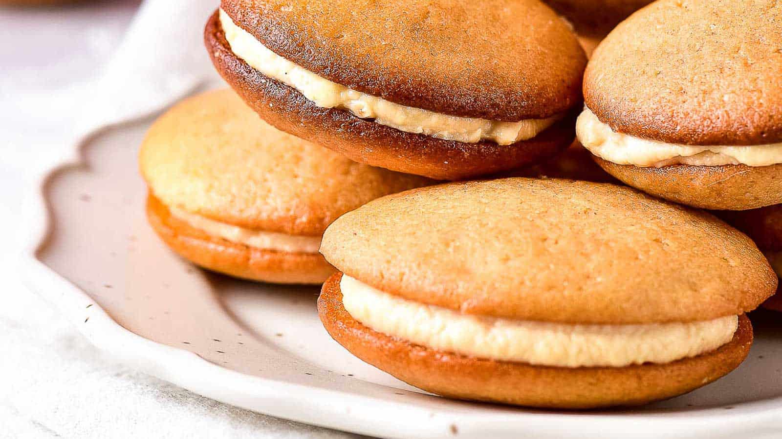 A plate of caramel sandwich cookies on a white plate.