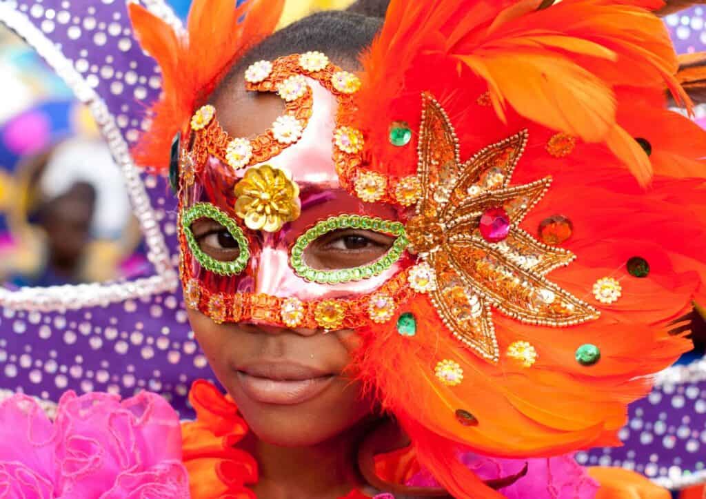 A young girl wearing a colorful mask at a carnival.