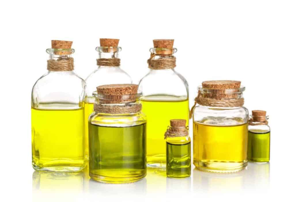 Carrier oils, including olive oil, in bottles on a white background.