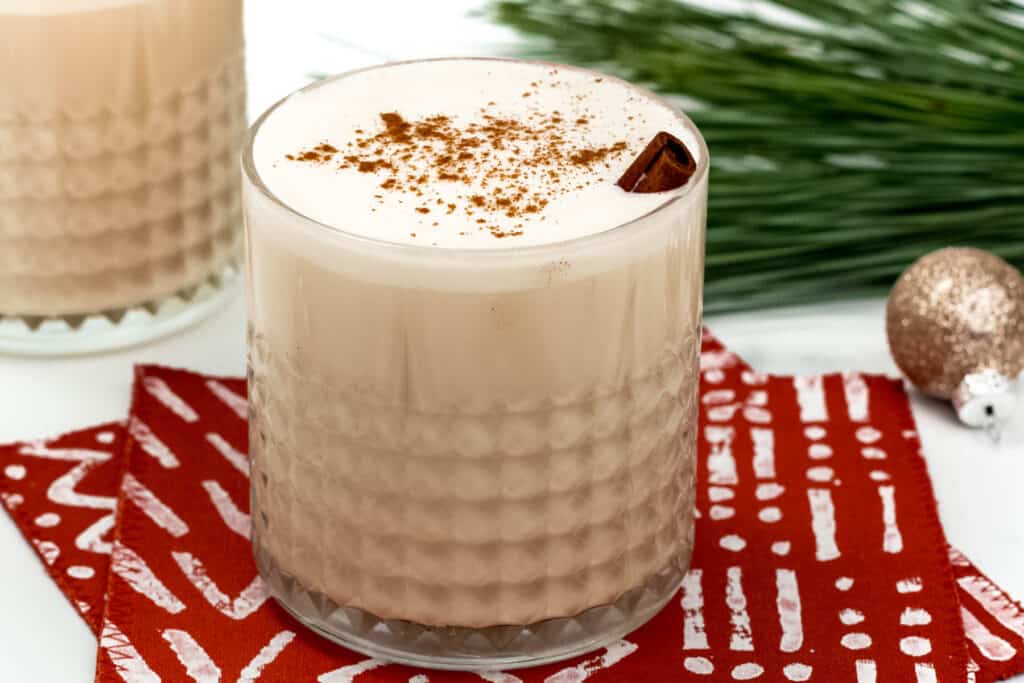 Two glasses of eggnog with cinnamon on a napkin.