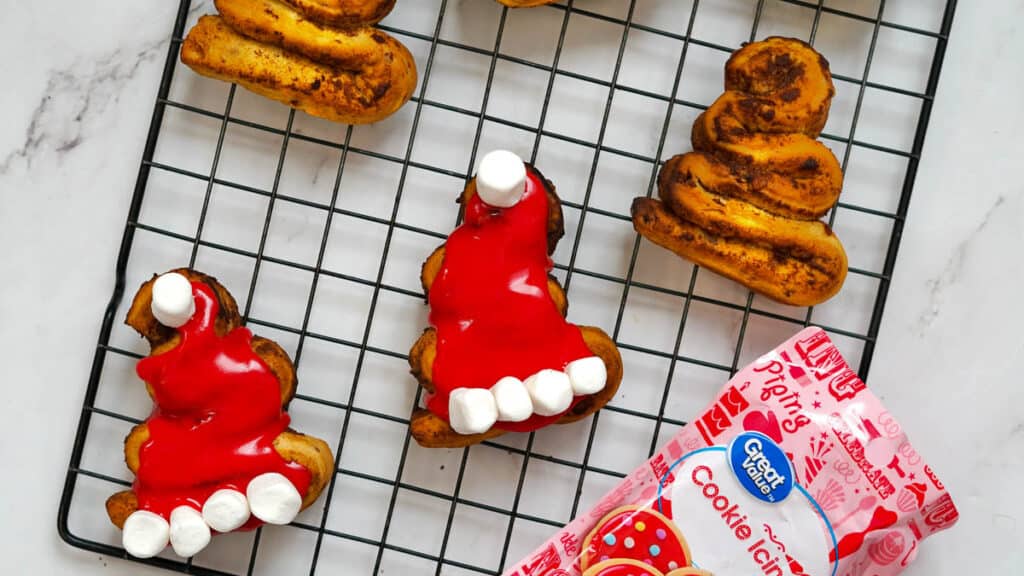 Cinnamon rolls on a plate with icing to make them look like santa hats.