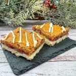 Two squares of cranberry bars on a slate plate.