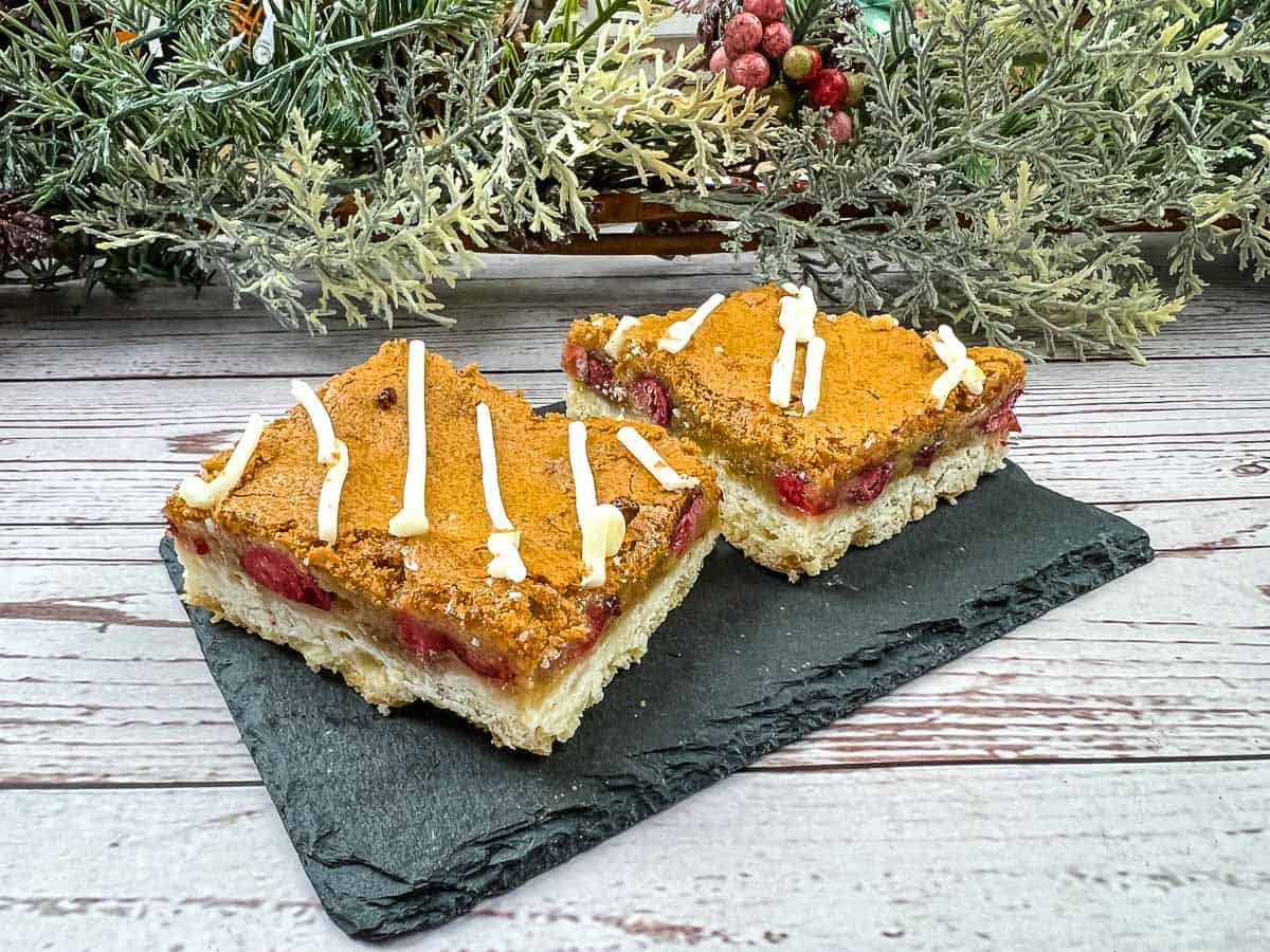 Two squares of cranberry bars on a slate plate.
