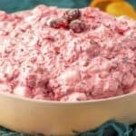 A bowl of pink cranberry dip with a wooden spoon.