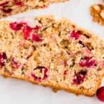 A slice of cranberry bread with cranberries and nuts.