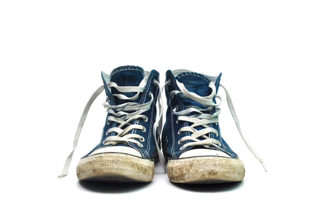 A pair of blue converse sneakers on a white background that need cleaning.