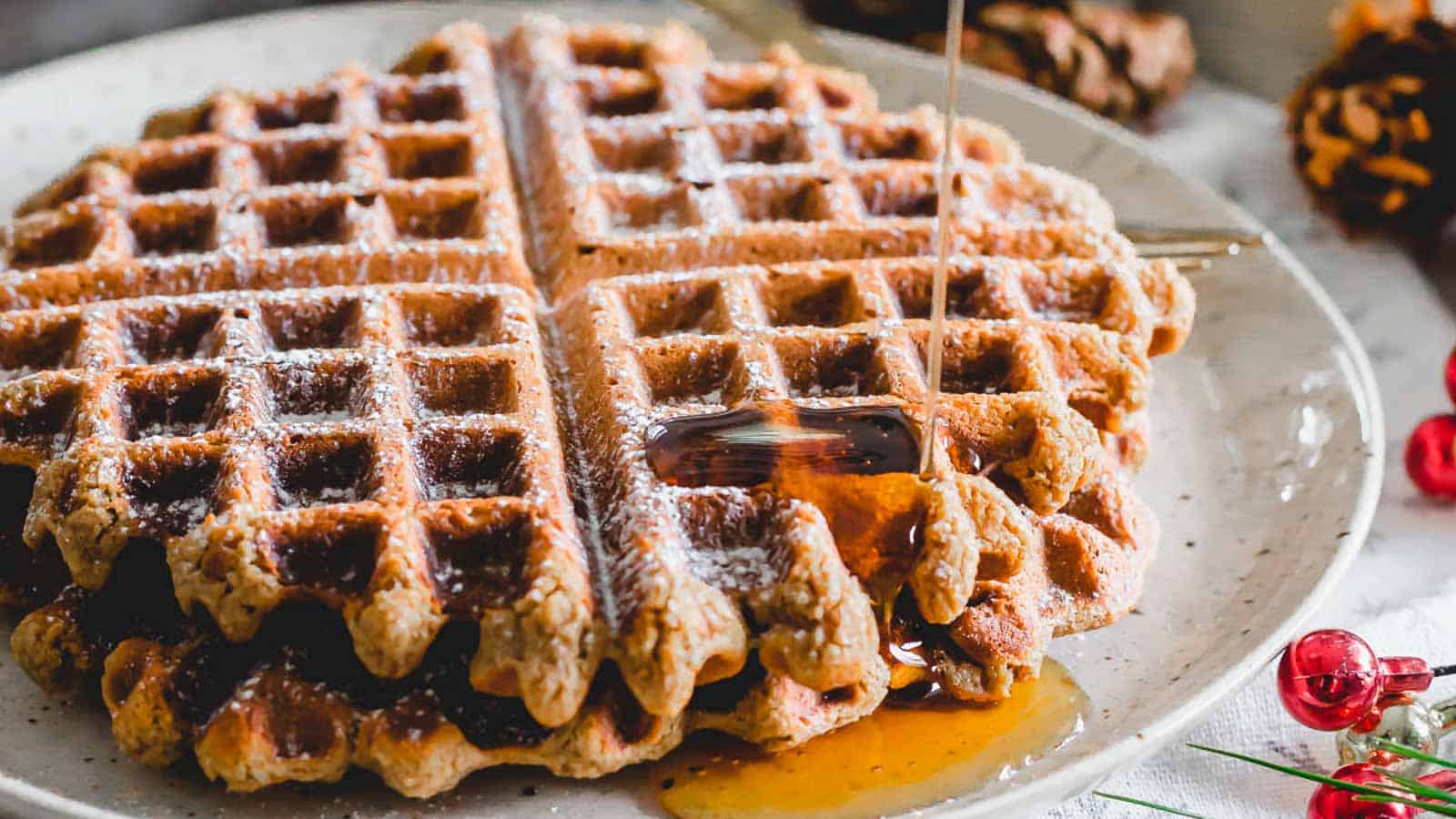 A plate of gingerbread waffles with syrup on it.