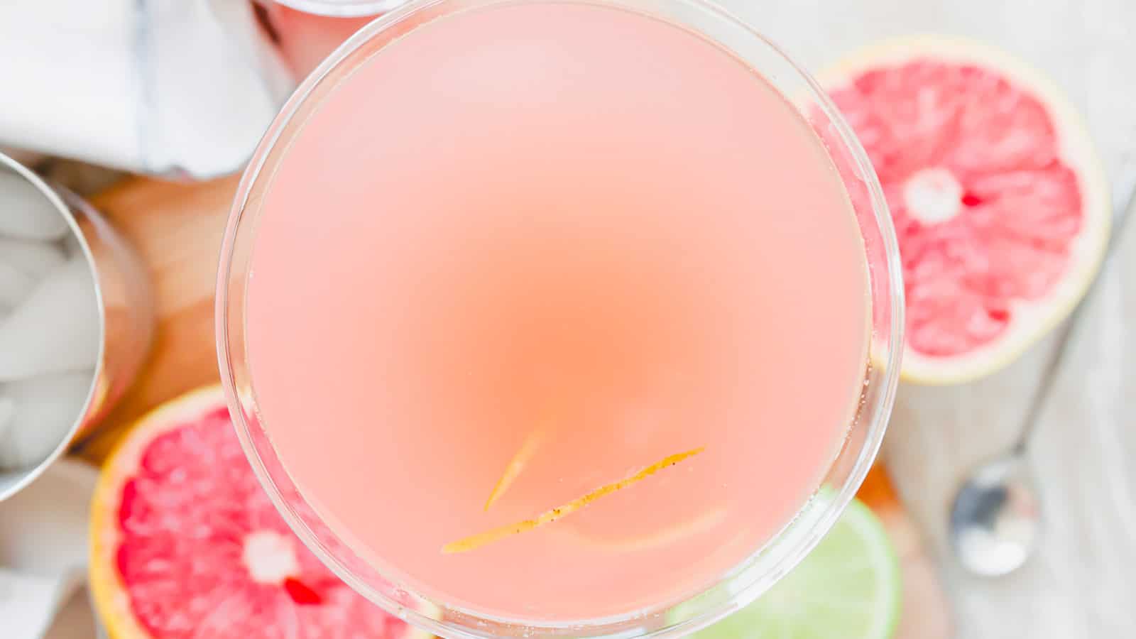 A pink martini with grapefruit slices and ice.