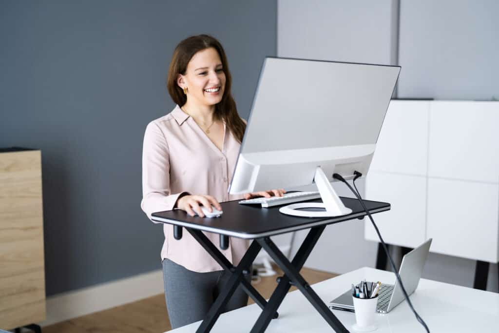 A woman working at a standing desk in front of a computer.