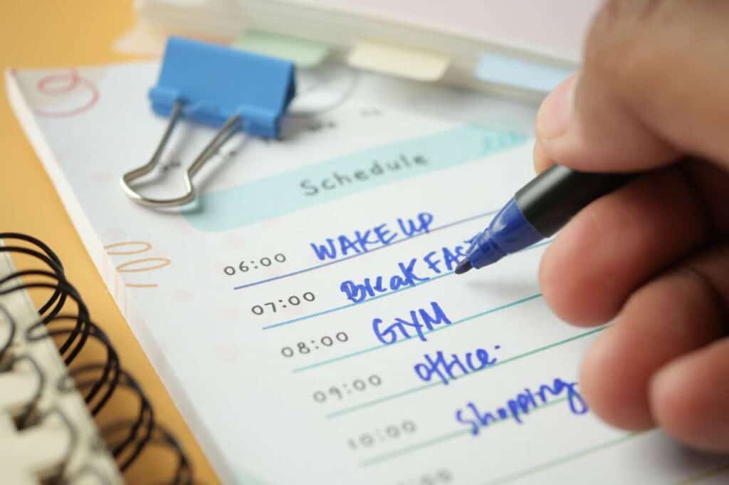 A person writing a schedule in a planner.