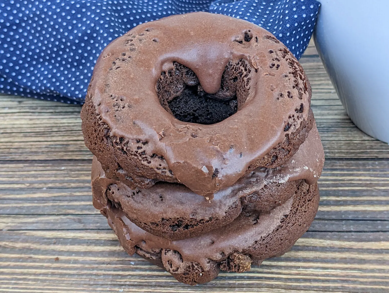 A stack of chocolate donuts on a wooden table.