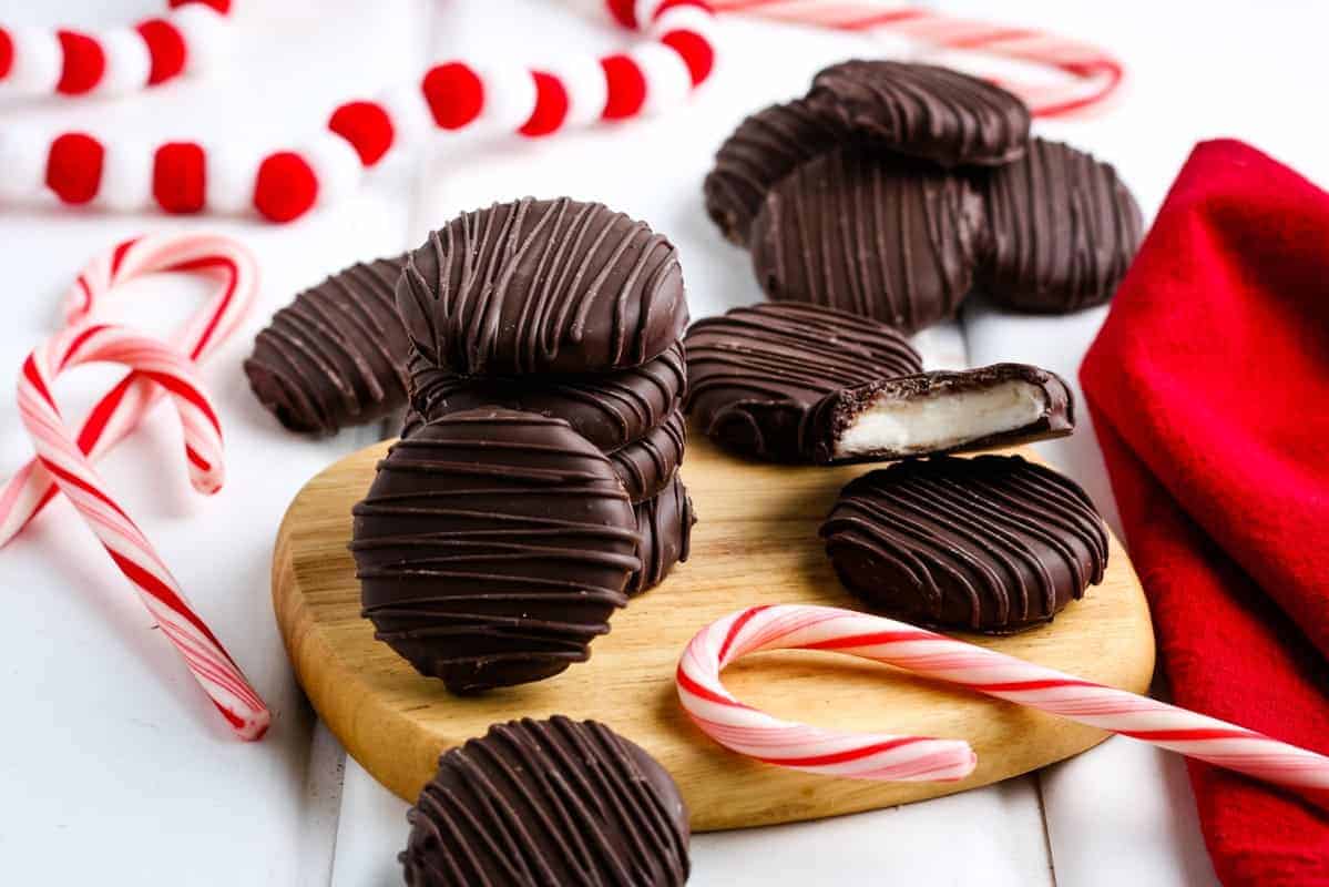 Chocolate covered peppermint patties on a wooden cutting board.