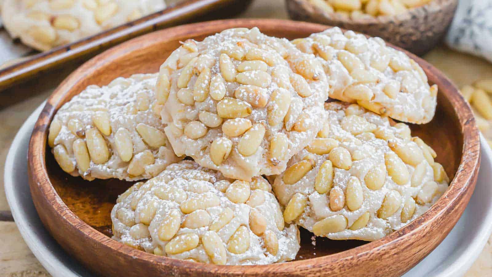 Almond cookies with powdered sugar in a wooden bowl.