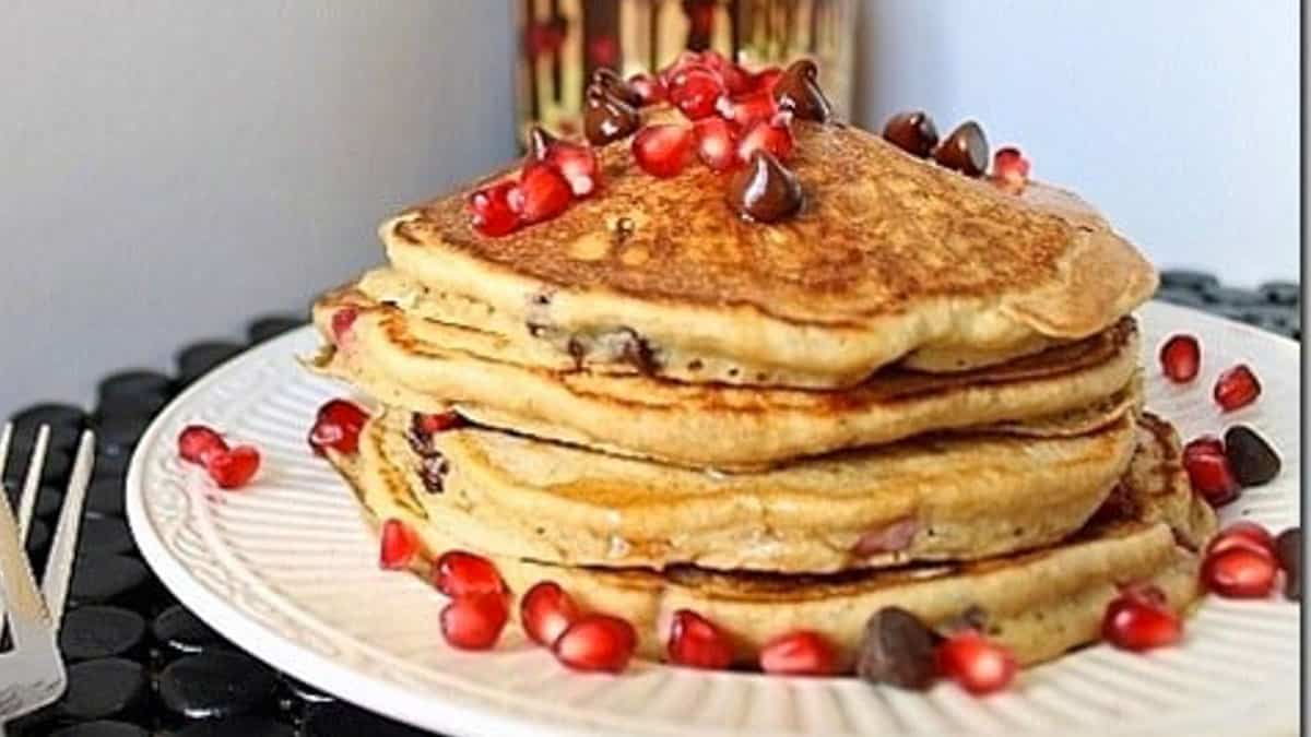 A stack of pancakes with pomegranate and chocolate chips.