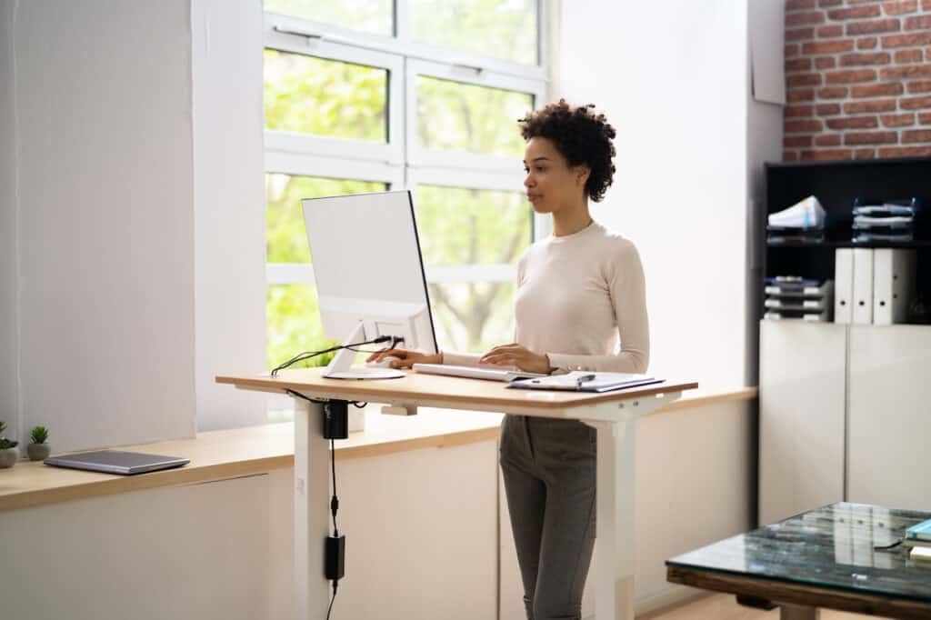 A woman utilizing a standing desk in an office environment.